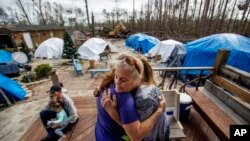 Diahnn "Shelly" Summers, right, embraces Lori Hogan, who is currently living in a tent in Summers' backyard months after Hurricane Michael hit in Youngstown, Fla, Wednesday, Jan. 23, 2019.