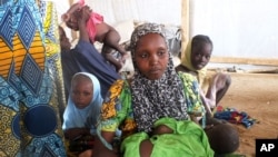 FILE - Refugees who fled their homes due to violence from the Islamic extremist group Boko Haram sit inside a refugee camp in Minawao, Cameroon, on Feb. 25, 2015. Tensions between host communities and displaced people in Cameroon have boiled over with killings and arson.