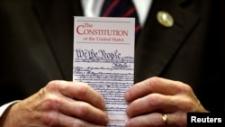 FILE - A member of Congress holds a copy of the U.S. Constitution in Washington, June 20, 2017. 