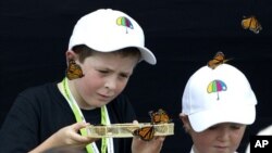 Cameron Lucas (L) and Tyler Bishop-Ward release some of the 185 butterflies during a memorial service in Christchurch February 22, 2012, to mark the 1st anniversary of the earthquake in Christchurch which killed 185 people.