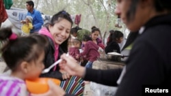 FILE - Migrants, mainly asylum-seekers sent back to Mexico from the U.S. under the "Remain in Mexico" program, are seen at a provisional campsite near the Rio Bravo in Matamoros, Mexico, Feb. 26, 2020.