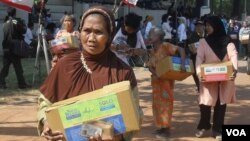 Para warga menerima paket sembako lebaran yang dibagikan oleh berbagai ormas lintas agama dan etnis di Solo, Minggu 12/8 (foto: Yudha Satriawan/VOA).