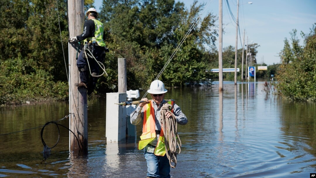 Dua pekerja berusaha memperbaiki jaringan listrik yang rusak akibat badai Matthew melanda Lumberton, North Carolina, Selasa (11/10).