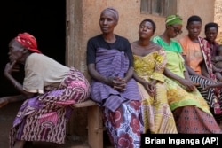 Women listen to Prudencienne Namukobwa, not pictured, as she performs akazehe, outside her house in Ngozi, Burundi, Friday, Sept. 20, 2024. (AP Photo/Brian Inganga)