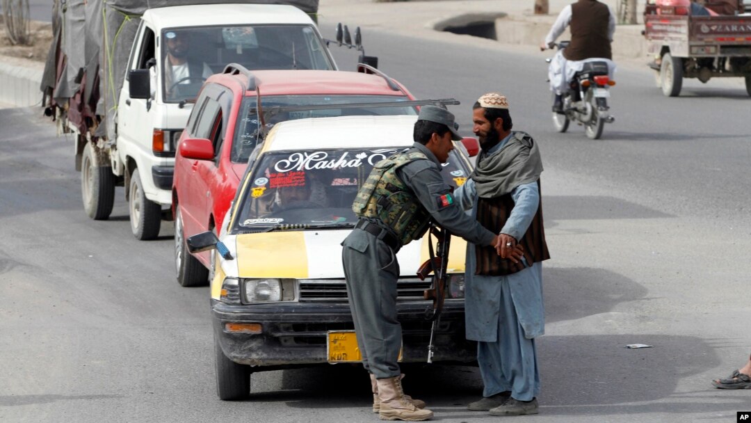 An Afghan policeman searches a passenger at a checkpoint in Kandahar, Jan. 26, 2016.