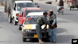 FILE - An Afghan policeman searches a passenger at a checkpoint in Kandahar, Afghanistan, Jan. 26, 2016. Four Afghan policemen were killed and another seven wounded when one of their colleagues opened fire on them in the volatile southern province of Kandahar.