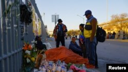 Migrants speak next to an altar outside the migrant detention center where several migrants died after a fire broke out late on Monday, in Ciudad Juarez, Mexico, March 29, 2023.