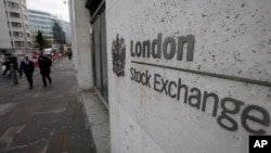 FILE - People walk past London's Stock Exchange, in London's City financial district. Global stocks tumbled Friday and oil fell below $80 a barrel after news of a possibly vaccine-resistant coronavirus variant.
