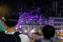 Anti-extradition bill protesters watch as demonstrators point laser pens at the police station in Sham Shui Po in Hong Kong, Aug. 14, 2019.