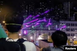 Anti-extradition bill protesters watch as demonstrators point laser pens at the police station in Sham Shui Po in Hong Kong, Aug. 14, 2019.