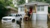 Bomberos llevan comida a los habitantes del barrio Tremont Park que quedaron atrapados por las inundaciones causadas por la tormenta tropical Debby, el martes 6 de agosto de 2024, en Savannah, Georgia.