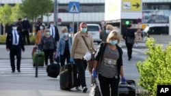 Romanian care workers with face masks accompanied by police and security arrive at the train station of Vienna's Schwechat airport, Austria, May 11, 2020.