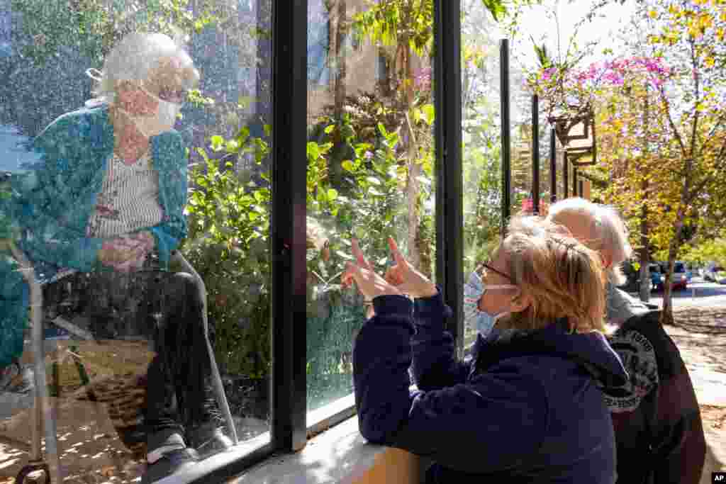 A woman, right, speaks with her 90-year-old mother, who suffered a stroke, through a window at the Premier Hospital, in Sao Paulo, Brazil. The hospital does not have any cases of COVID-19, but closed visits to patients to prevent possible contagion.