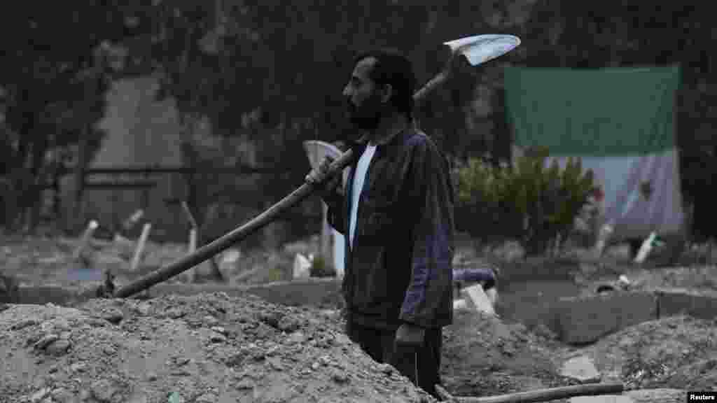 Abu Saleh, a 48-year-old man, holds a shovel in a cemetery in Deir al-Zor, eastern Syria, November 25, 2013.