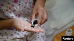 FILE - A woman suffering from cervical cancer takes her medicine at a treatment facility in Beijing, China, June 23, 2016.