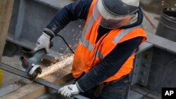 FILE - Sparks fly as a construction worker uses a grinder to cut through steel reinforcing bars in New York, Feb. 1, 2016. 