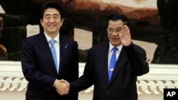 Cambodian Prime Minister Hun Sen, right, shakes hands with Japanese Prime Minister Shinzo Abe, left, as they pose for photos during a welcome ceremony in Peace Palace, in Phnom Penh, Cambodia, Saturday, Nov. 16, 2013. Abe is on a two-day official visit. (AP Photo/Heng Sinith)