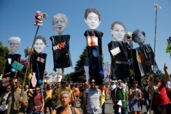Anti-G-7 activists carry pictures of the G-7 leaders during a protest in Hendaye, France, Aug. 24, 2019.