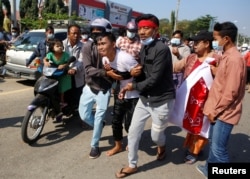 An injured protester is helped by his fellow protesters, at a rally against the military coup and to demand the release of elected leader Aung San Suu Kyi, in Naypyitaw, Myanmar, Feb. 9, 2021.