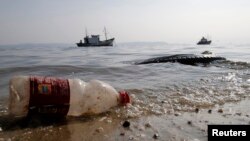 A plastic bottle and a tire are seen near a fishing boat on Fundao beach in the Guanabara Bay in Rio de Janeiro, March 13, 2014. 