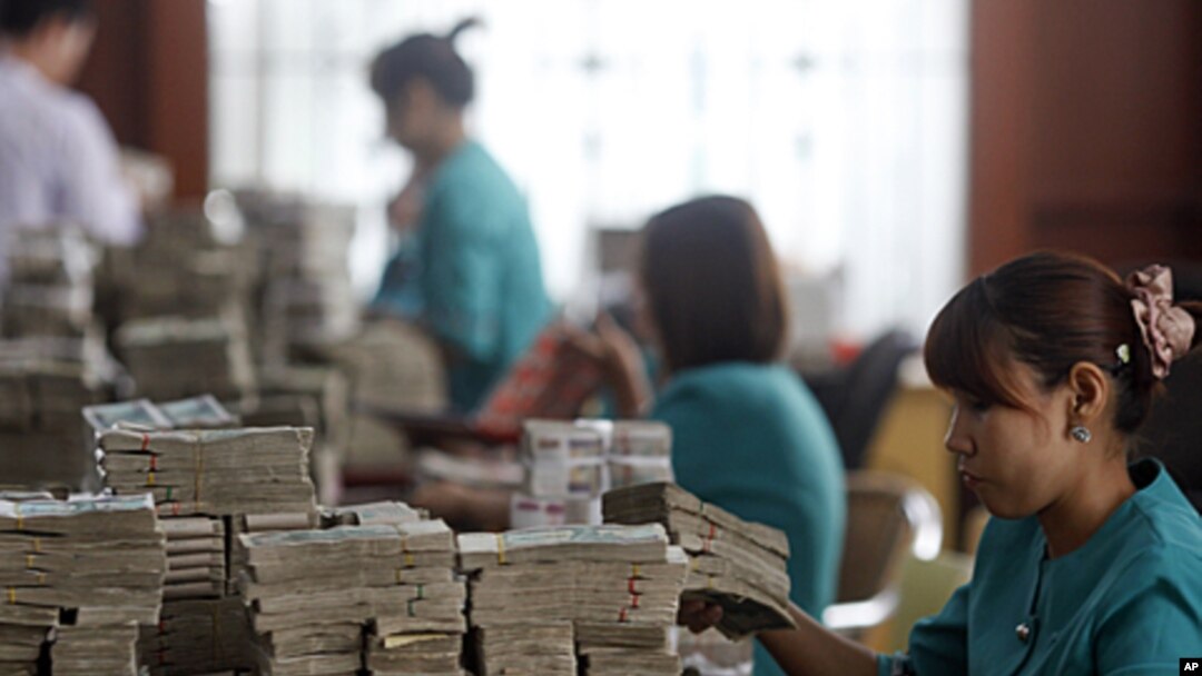Workers count Burma's kyat banknotes at the office of a local bank in Rangoon, April 2, 2012. 