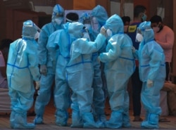 Health workers and volunteers in personal protective suits wait to receive patients outside a COVID-19 hospital that was set up at a Sikh Gurdwara in New Delhi, India, May 10, 2021.