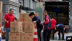 Workers load and pack gift boxes for the upcoming Mid-Autumn Festival, outside a supermarket in Beijing on Sept. 11, 2024.