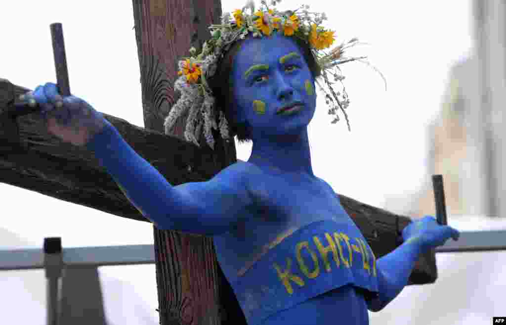 A girl symbolizing the Ukrainian Constitution is &quot;crucified on the cross by the acting power&quot; during a performance called by Guy Fawkes&#39; activists in front of the Constitutional Court building in Kyiv. The activists call on Ukrainians to take action to defend the Constitution ahead of Constitution Day held on June 28.