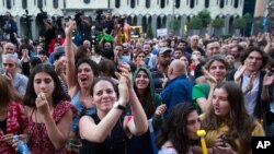 People applaud and listen to a speaker during a protest as opposition demonstrators gather in front of the Georgian Parliament building in Tbilisi, Georgia, June 24, 2019. 