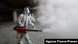 Staff members wearing personal protective equipment (PPE) spray disinfectant outside a shopping mall in Xi&#39;an in north China&#39;s Shaanxi province.