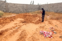 A member of security forces affiliated with the Libyan Government of National Accord's Interior Ministry stands at the reported site of a mass grave in Tarhuna, about 65 kilometers southeast of Tripoli, June 11, 2020.