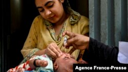 লাহোরে পোলিও টিকাদান অভিযানের সময় একজন স্বাস্থ্যকর্মী একটি শিশুকে টিকা দিচ্ছেন। সেপ্টেম্বর ২০, ২০২১। 