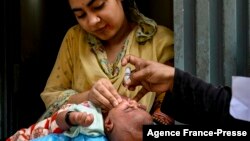FILE - A health worker administers polio vaccine drops to a child during a polio vaccination campaign in Lahore on Sept. 20, 2021. 