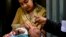 FILE - A health worker administers polio vaccine drops to a child during a polio vaccination campaign in Lahore on Sept. 20, 2021. 