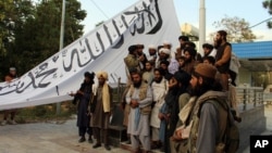 Taliban fighters pose for a photo while raising their flag at Ghazni provincial governor's house, in Ghazni, southeastern Afghanistan, Aug. 15, 2021. 