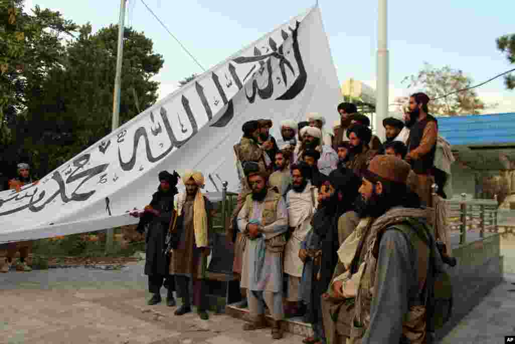 Para pejuang Taliban berpose untuk foto bersama sambil mengibarkan bendera Taliban di rumah gubernur provinsi Ghazni, di Ghazni, Afghanistan tenggara, 15 Agustus 2021. (Foto: AP)