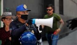 A police officer warns people to stay home as a precaution against the spread of the new coronavirus, in the historic center of Mexico City, April 1, 2020.