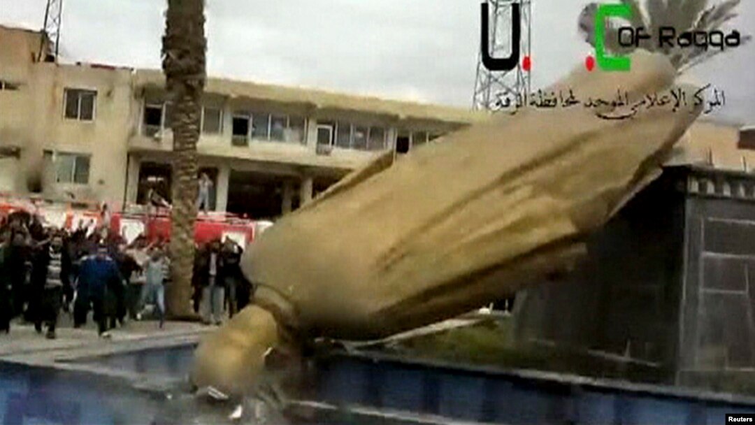 A statue of President Bashar Al-Assad's father, Hafez Al-Assad, is pulled down as people celebrate in Raqqa Mar. 4, 2013.