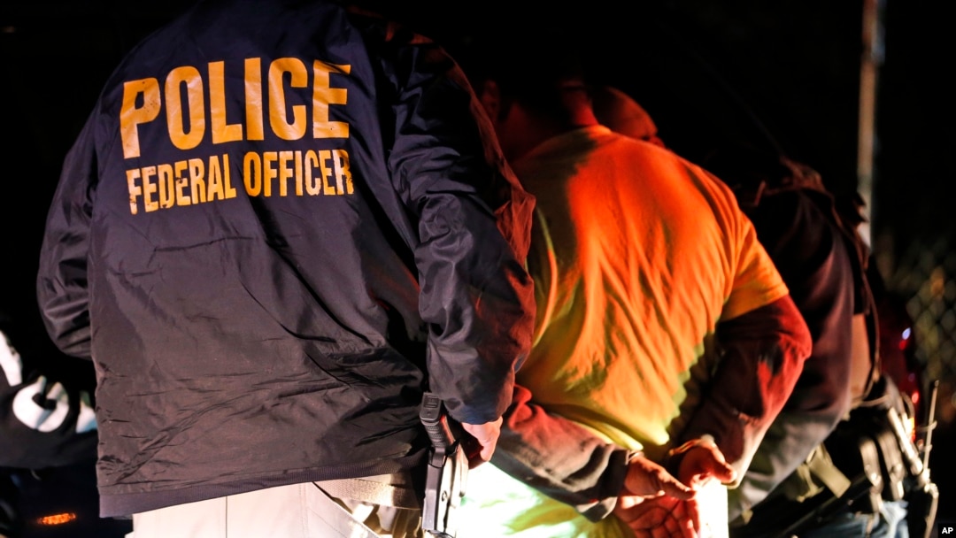 FILE - U.S. Immigration and Customs Enforcement agents surround and detain a person during a raid.