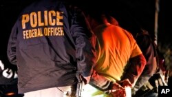 Para agen Dinas Penegakan Imigrasi dan Bea Cukai menahan seseorang saat razia imigran di Richmond, Va., 22 Oktober 2018. 