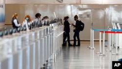 An American Airlines ticketing agent helps a woman as she approaches the counter in Denver International Airport as travelers deal with the effects of the new coronavirus, June 10, 2020, in Denver. 