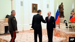 资料照片：俄罗斯总统普京与来访的中国国防部长李尚福握手。(2023年4月16日）