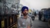 Farmer Harinder Singh, 28, stands for a photograph next to his tractor parked on a highway during a protest against new farm laws, at the Delhi-Haryana state border, India, Dec. 2, 2020. 