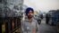 Farmer Harinder Singh, 28, stands for a photograph next to his tractor parked on a highway during a protest against new farm laws, at the Delhi-Haryana state border, India, Dec. 2, 2020. 