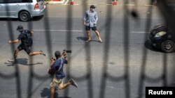 FILE - Pro-democracy protesters and a journalist run as riot police officers advance them during a rally against the military coup in Yangon, Myanmar, Feb. 27, 2021. 