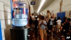 FILE - A bottled water dispenser sits in a hallway at Gardner Elementary School in Detroit, Sept. 4, 2018. Some 50,000 Detroit public school students will drink water from coolers, not fountains, after the discovery of elevated levels of lead or copper.