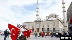 A flag seller waits for customers in front of the 17th century Ottoman era New Mosque (Yeni cami) in Istanbul, Turkey, May 4, 2016. 