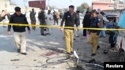 Security officials examine the site of a bomb blast in Kohat, Khyber Pakhtunkhwa province, Pakistan, Feb. 23, 2014.