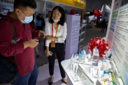 FILE - A visitor wearing a face mask looks at a model of a coronavirus and boxes for COVID-19 vaccines at a display by Chinese pharmaceutical firm Sinopharm at the China International Fair for Trade in Services in Beijing, Sept. 5, 2020.