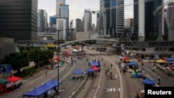 Para demonstran pro-demokrasi berjalan keluar tenda di jalan utama yang mengarah ke distrik keuangan Central di Hong Kong (10/10). 